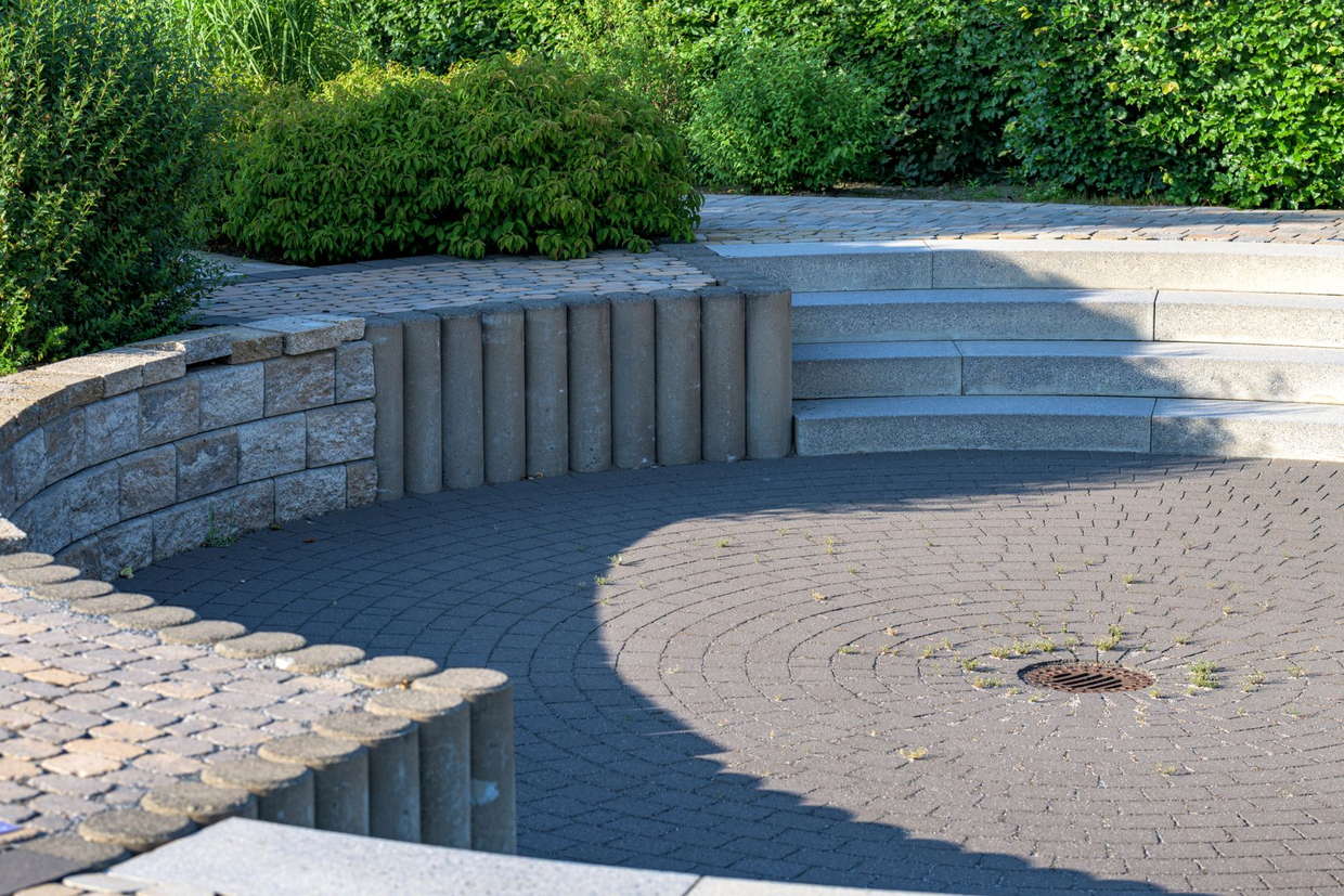 Licensed stock photograph: a curved block retaining wall with a stone cap, meeting a run of steps and a paver terrace.